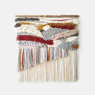 Boho red, grey and warm beige woven tapestry with tassels presented in scandi boho interior.