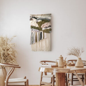 light beige and olive green woven wall hanging with long tassels presented in a beige modern living room