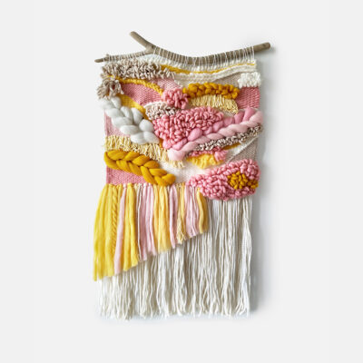 yellow and pink woven wall hanging with long beige tassels